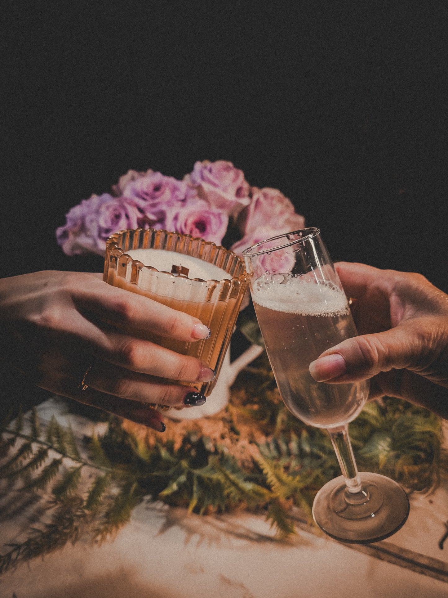 Two glasses being clinked together with flowers in the background