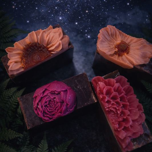 Four floral soap bars with different colors on a dark background